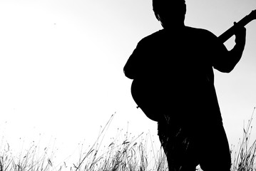 Abstract beautiful man playing Guitar in the foreground on clear sky background.