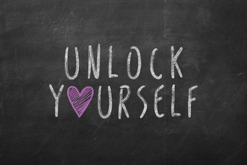 Obraz premium unlock yourself text hand-written on black chalkboard