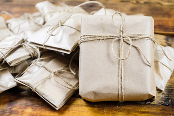 Close-up many gifts wrapped kraft paper on wooden background. One big present front view