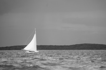 A lone Bahamian C-Class sailboat racing in a regatta near Little Farmer's Cay in the Bahamas.