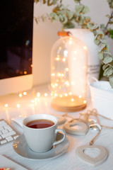 A cup of tea and decorative hearts on a wooden table. Boke in the background