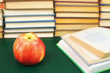 Apple on the green table and open books