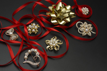 still life with brooches with ribbon and bow isolated on black
