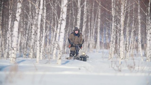 Man overcoming deep snow on a mini snowmobile in the snowy forest