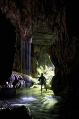 A man standing next to an underground waterfall near the entrance of a glow worm cave in New Zealand.