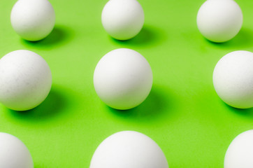Symmetry of white eggs on bright light green background.