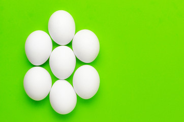 Symmetry of white eggs on bright light green background.
