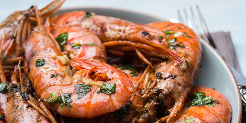 Grilled shrimps with parsley on pastel turqouise background. Shellfish dish