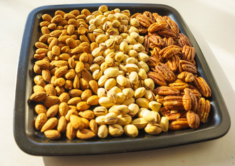 Nuts almonds, pistachios and pecans on black plate, close-up, set.  