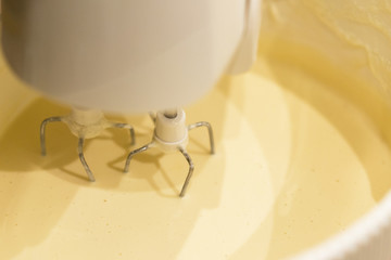 A kitchen mixer with yellow egg yolks mixed with sugar in a modern kitchen. Shot at an angle with...
