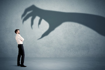 Fototapeta premium Business person afraid of a big monster claw shadow concept