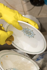 Woman's hands in the gloves wash plate horizontal closeup