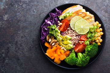 Buddha bowl dish with chicken fillet, brown rice, avocado, pepper, tomato, broccoli, red cabbage,...