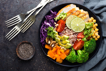 Buddha bowl dish with chicken fillet, brown rice, avocado, pepper, tomato, broccoli, red cabbage,...