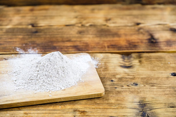 Close-up heap with wheat flour coarse on a wooden board. Left on the photo.