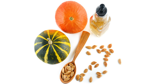 Oil, seeds and pumpkin fruits isolated on white background. Wide photo