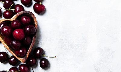 Fresh sweet cherries in wooden bowl in the shape of  heart, top view