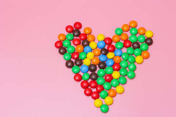 a colorful heart of sweets on a pink background. Sweet heart. Candy heart.