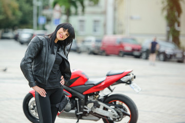 Fototapeta na wymiar A biker girl in a leather jacket on a motorcycle posing in the city