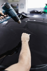 Car tinting - Worker applying tinting foil on car window. Selective focus.