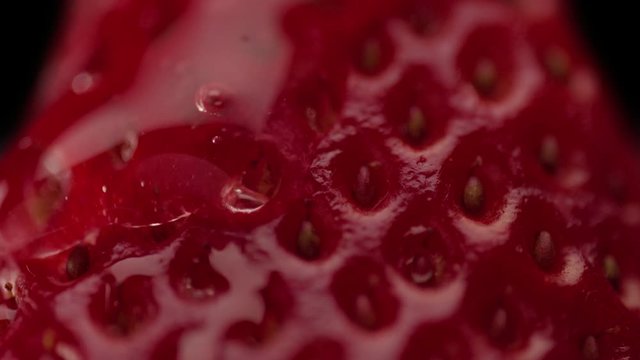 macro of strawberry texture and a trandparent drop on it moving slowly