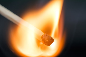the flame of a burning match on a dark  blurred neutral background crisis intervention concept, close up,  selective focus
