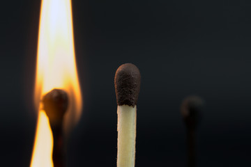 the flame of a burning match on a dark  blurred neutral background disability pension concept, close up,  selective focus