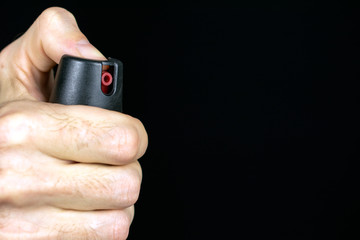 Fototapeta premium pepper gas in the hand of a young man in a black jacket CS spray self-defense Tear gas concept, copy space, close up, selective focus , blurred dark background