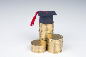 graduation mortarboard and golden coins on white background, education concept close up, selective focus