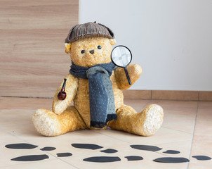 Sherlock Holmes teddy bear detective investigates - black footprints on the floor