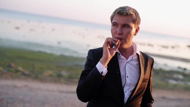 Man smoking at the beach at sunset