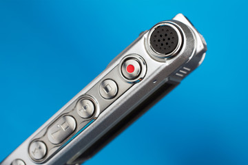 Fototapeta premium dictaphone closeup of a red record button selective focus blue blurred background journalism concept
