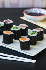A selection of sushi rolls with salmon, tuna and cucubmer with soy sauce dip.