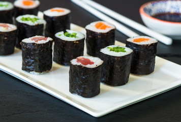 A selection of sushi rolls with salmon, tuna and cucubmer with soy sauce dip.