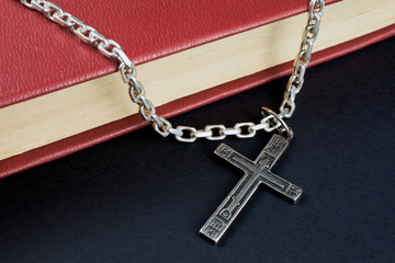 Fototapeta na wymiar Closeup of Christian cross with silver chain on holy Bible book with a red cover. ready for read and have relationship with god faith, spirituality and religion concept. selective focus,