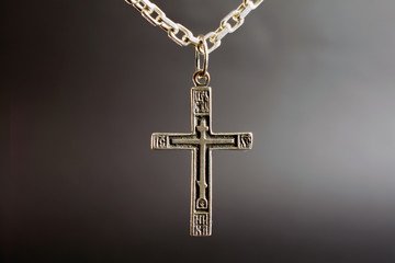 christian cross on a silver chain, faith, spirituality and religion concept. selective focus, dark blurred  background