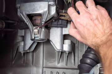 repairer hand with pliers fix the electric motor of the washing machine, replacement of brushes,...
