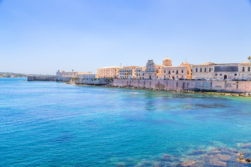 Fototapeta na wymiar Syracuse, Italy. Quay of the island of Ortygia: Maniace Castle (1232-1240) and the Church in the name of the Holy Spirit, 1727 - 1797. The island is wholly included in the UNESCO list