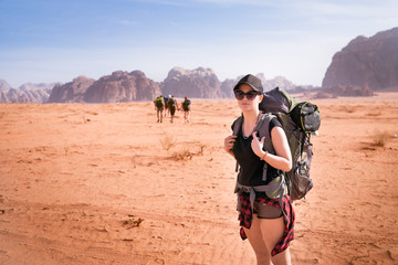 Tourist woman with friends in a desert. Jordan natural park Wadi Rum. Backpacker on the road. Woman...