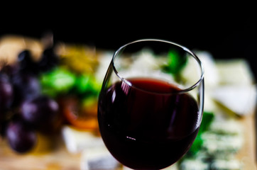 Red wine and set of different cheeses on a wooden board, delicious snack