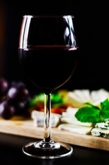 Red wine and set of different cheeses on a wooden board, delicious snack
