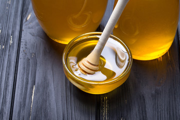 Honey in jar with honey dipper on wooden background