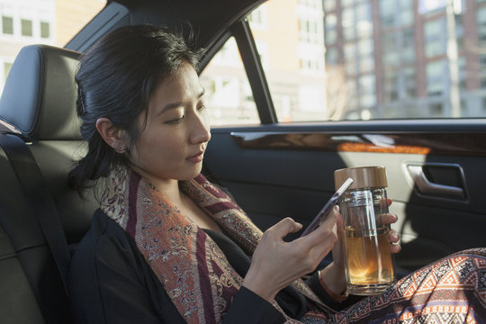 Businesswoman looking at smartphone while sitting in car 