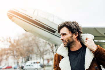 handsome man with old airplane behind outside