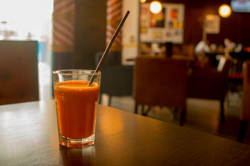 carrot juice in a glass with a straw on the table in a cafe