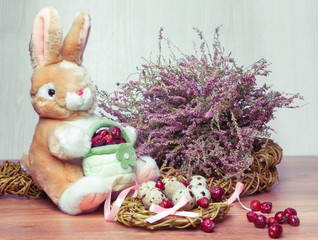 rabbit toy among Easter eggs and heather bouquet,