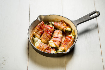 Meat bacon slices roasted in pan. White wooden background, natural light