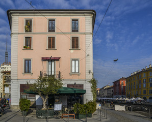 Builings and flea market along the Naviglio Grande canal in bohemian Navigli district of Milan, Italy. The canal is 50km long