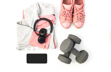 Top view fitness and sports clothes and accessories for females on white background: Sneakers, headphones, cell phone, dumbbells