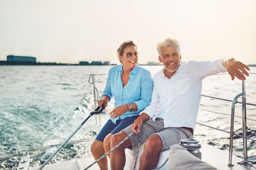 Smiling mature couple sailing their boat on a sunny afternoon © Flamingo Images